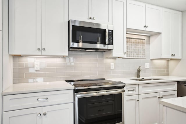 329 Geneva Ave N Unit 212, Oakdale, MN 55128 - kitchen featuring white cabinetry, appliances with stainless steel finishes, a sink, light countertops, and backsplash