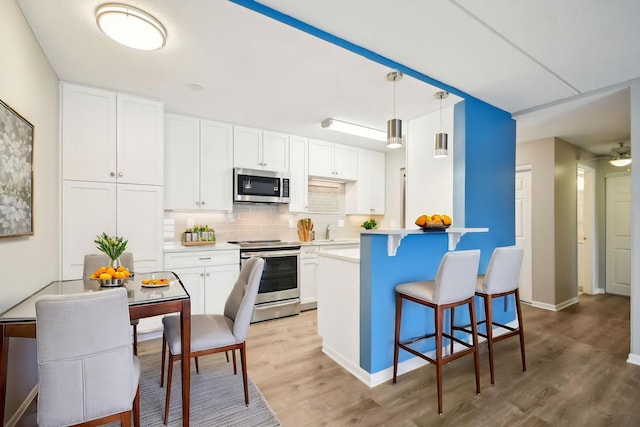 329 Geneva Ave N Unit 212, Oakdale, MN 55128 - kitchen with backsplash, light wood-type flooring, a kitchen bar, and stainless steel appliances