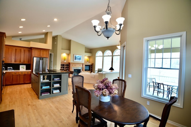 13258 Derryglenn Ct, Rosemount, MN 55068 - dining area with a chandelier, light wood finished floors, high vaulted ceiling, a glass covered fireplace, and recessed lighting