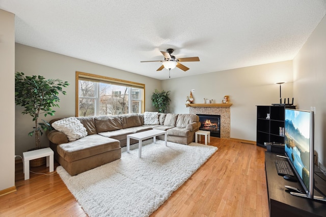 640 Falcon Ridge Rd, Woodbury, MN 55125 - living area featuring ceiling fan, light wood-type flooring, a lit fireplace, a textured ceiling, and baseboards