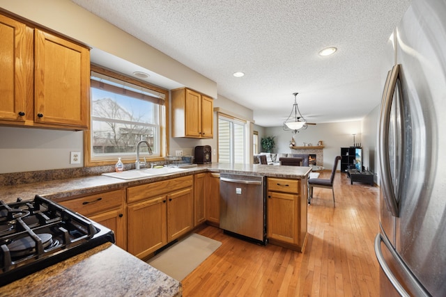 640 Falcon Ridge Rd, Woodbury, MN 55125 - kitchen with appliances with stainless steel finishes, a sink, a textured ceiling, a peninsula, and open floor plan
