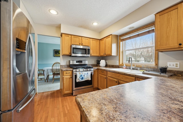 640 Falcon Ridge Rd, Woodbury, MN 55125 - kitchen featuring stainless steel appliances, a sink, light wood finished floors, a textured ceiling, and brown cabinets