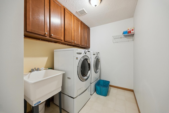 640 Falcon Ridge Rd, Woodbury, MN 55125 - laundry area with washer and clothes dryer, cabinet space, a textured ceiling, baseboards, and light floors