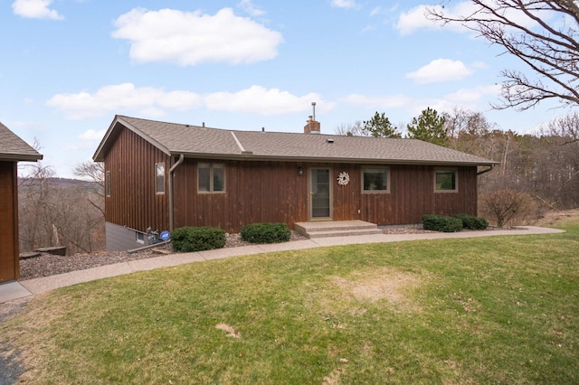ranch-style home featuring a chimney, a front lawn, and roof with shingles