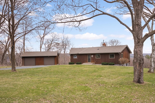 ranch-style house with a chimney, a front lawn, driveway, an outbuilding, and a garage