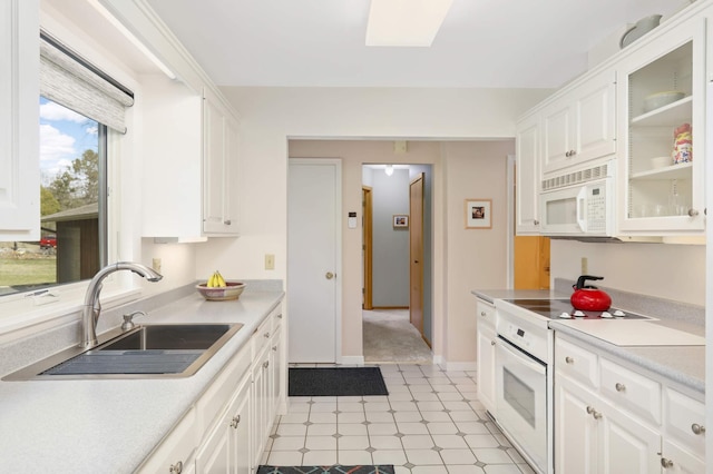 kitchen featuring white cabinets, a sink, white appliances, and light countertops