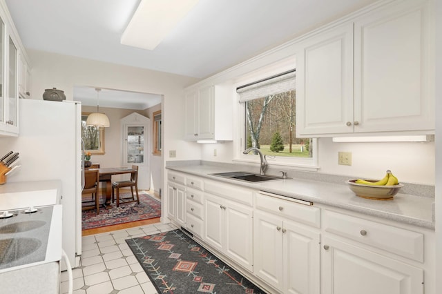 kitchen featuring white cabinets, a sink, light floors, light countertops, and decorative light fixtures