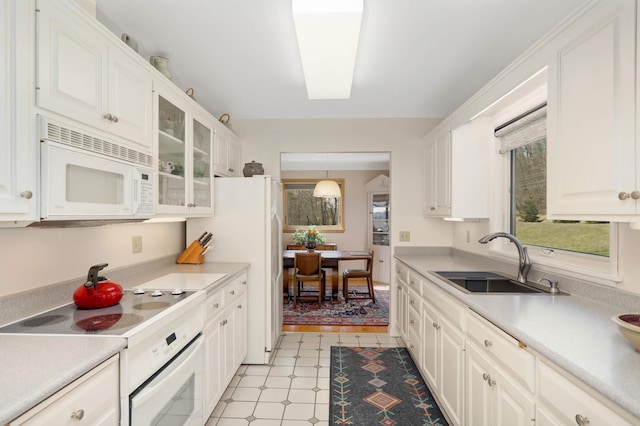 kitchen featuring white cabinets, a sink, white appliances, and glass insert cabinets