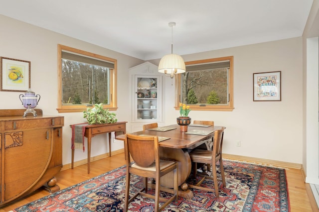 dining space with baseboards and light wood-style floors