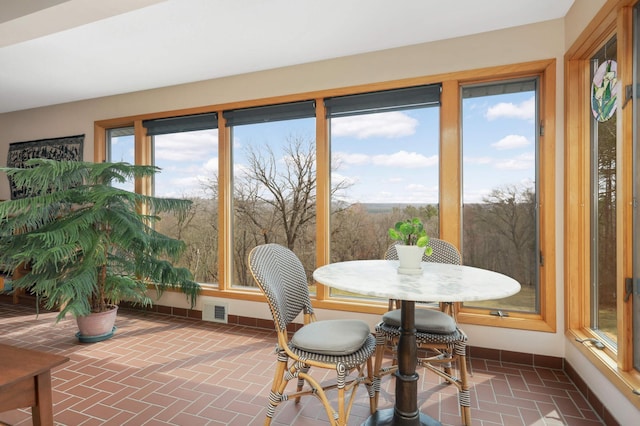 sunroom / solarium featuring baseboards, brick floor, and visible vents