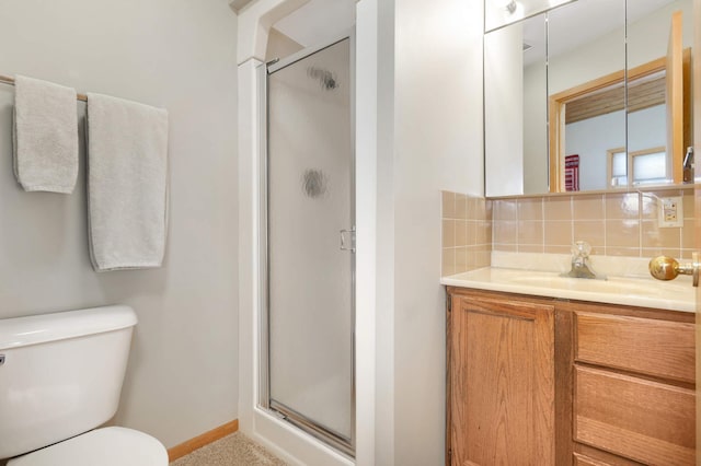 bathroom featuring toilet, vanity, baseboards, tasteful backsplash, and a stall shower