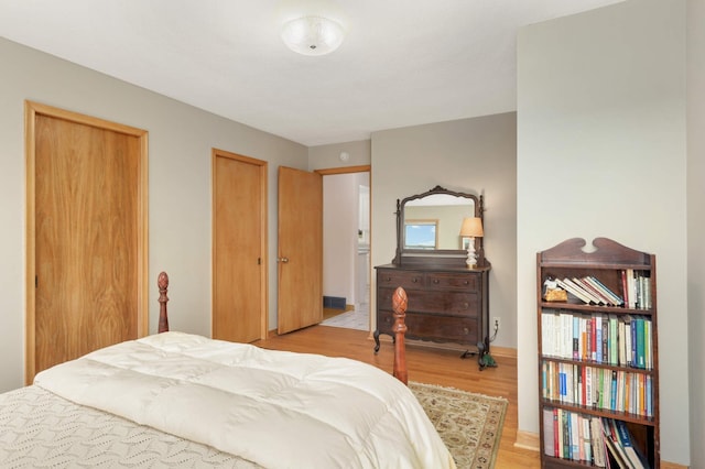 bedroom with two closets and light wood finished floors