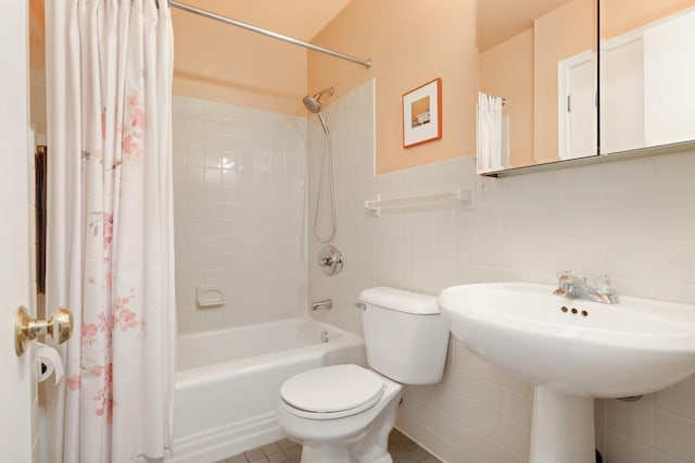 bathroom featuring tile walls, a sink, shower / bathtub combination with curtain, and toilet