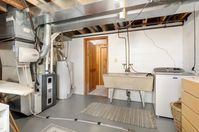 unfinished basement with washing machine and clothes dryer, concrete block wall, water heater, and a sink