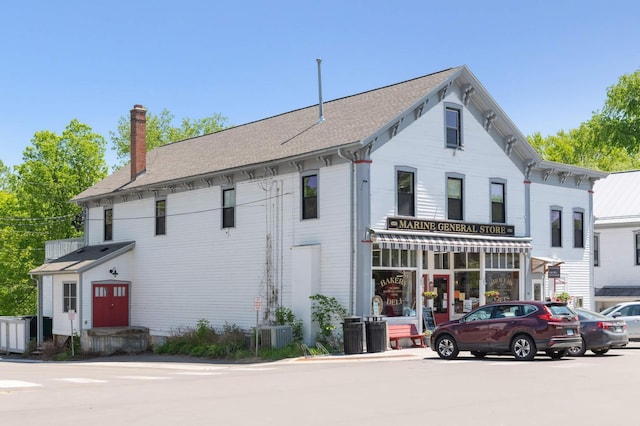 view of front of home with a shingled roof and a chimney