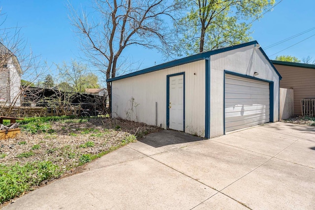 detached garage featuring driveway and fence