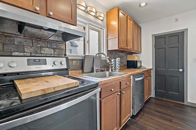 kitchen featuring stainless steel appliances, under cabinet range hood, a sink, dark wood finished floors, and decorative backsplash