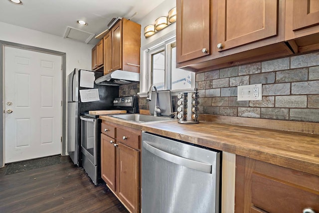 kitchen with stainless steel appliances, wooden counters, a sink, dark wood finished floors, and brown cabinetry