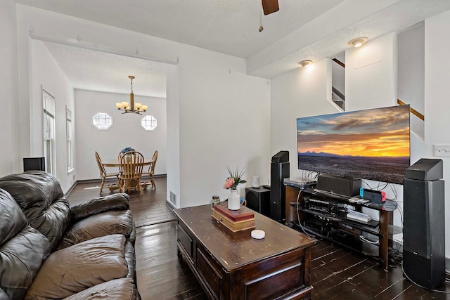 living area featuring dark wood-style floors, a chandelier, ceiling fan, and a textured ceiling