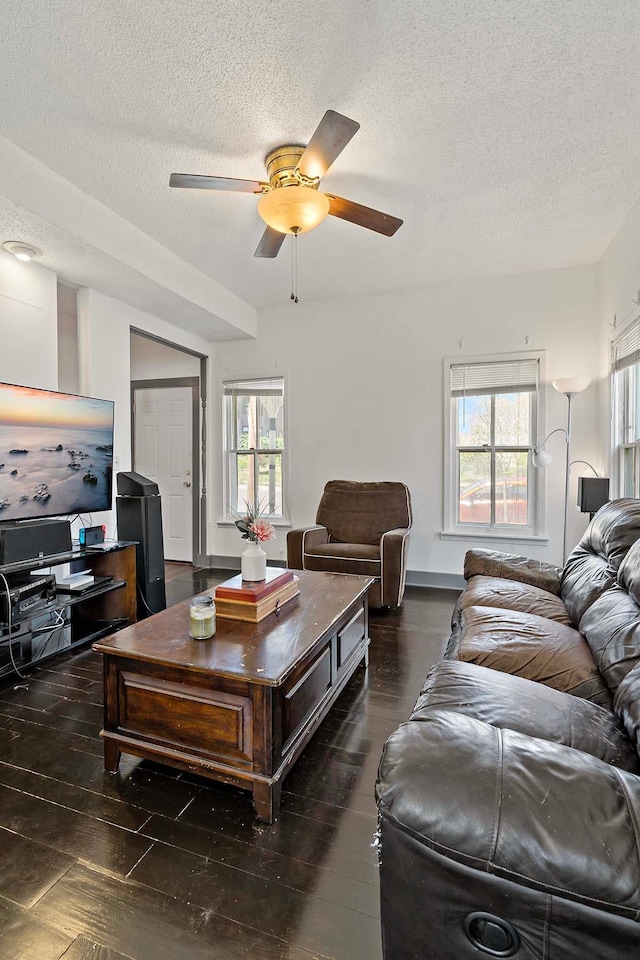 living area featuring a ceiling fan, plenty of natural light, wood finished floors, and a textured ceiling