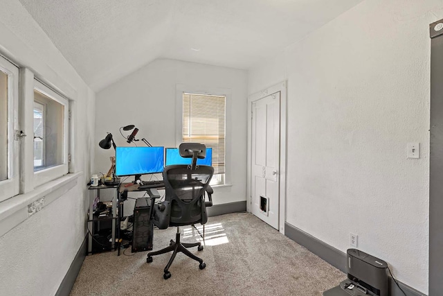 office space with vaulted ceiling, carpet floors, baseboards, and a textured wall