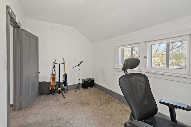 carpeted office space featuring vaulted ceiling and baseboards