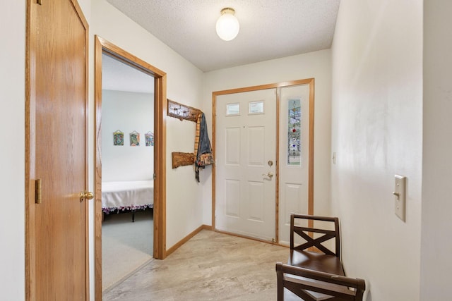 entryway featuring light carpet, a textured ceiling, and baseboards