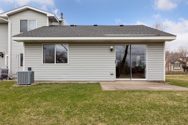 rear view of property with a yard, central AC unit, roof with shingles, and a patio area