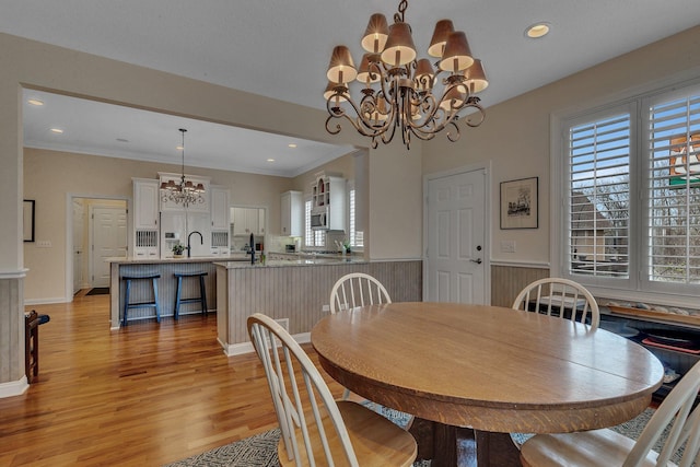 dining room featuring a chandelier, plenty of natural light, light wood finished floors, recessed lighting, and wainscoting