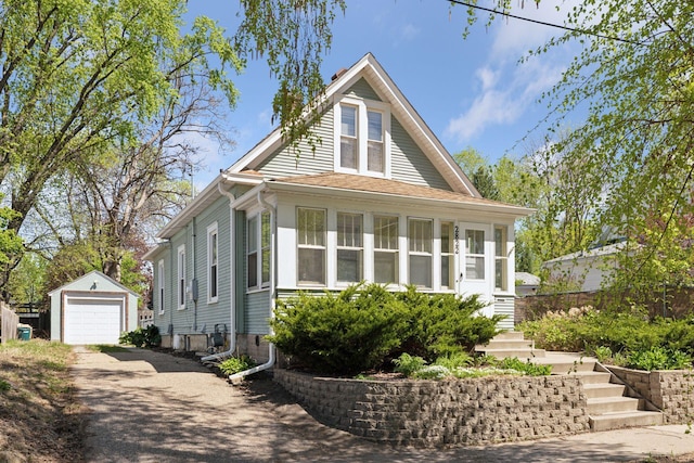 2822 29th St, Minneapolis, MN 55406 - view of front of house featuring asphalt driveway, an outdoor structure, a detached garage, a sunroom, and stairway