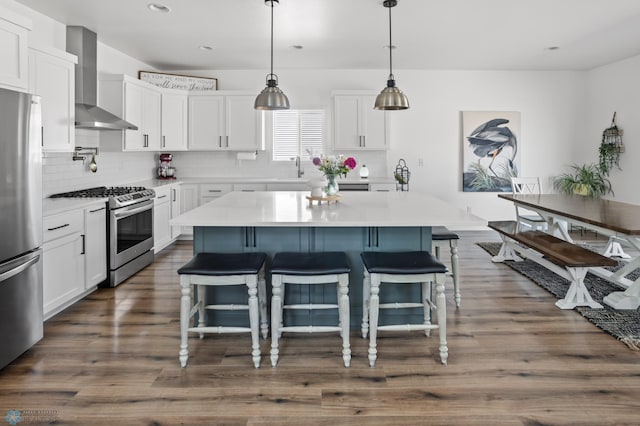 5497 11th St W, West Fargo, ND 58078 - kitchen with stainless steel appliances, white cabinetry, decorative backsplash, wall chimney range hood, and a breakfast bar
