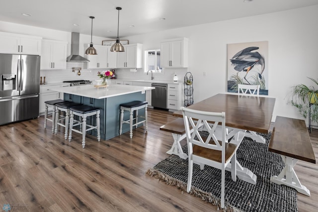 5497 11th St W, West Fargo, ND 58078 - kitchen featuring decorative backsplash, wall chimney exhaust hood, appliances with stainless steel finishes, and a breakfast bar area