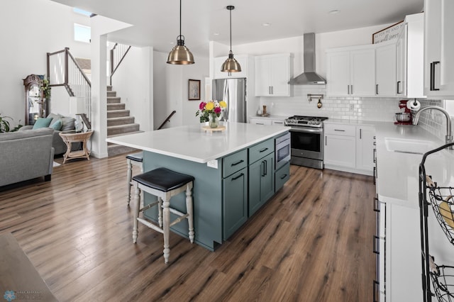 5497 11th St W, West Fargo, ND 58078 - kitchen with white cabinets, stainless steel appliances, a sink, dark wood-type flooring, and wall chimney exhaust hood