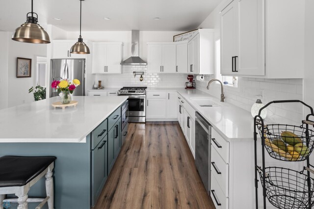 5497 11th St W, West Fargo, ND 58078 - kitchen featuring a sink, dark wood finished floors, white cabinetry, wall chimney range hood, and appliances with stainless steel finishes