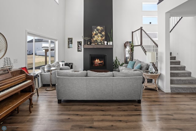 5497 11th St W, West Fargo, ND 58078 - living room featuring stairway, a towering ceiling, dark wood-style floors, and a lit fireplace