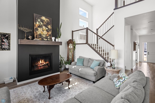 5497 11th St W, West Fargo, ND 58078 - living room with stairs, wood finished floors, a glass covered fireplace, baseboards, and a high ceiling