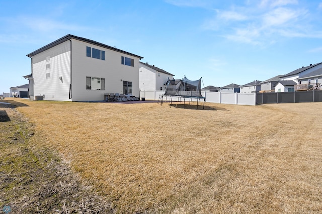 5497 11th St W, West Fargo, ND 58078 - back of house featuring a trampoline, a lawn, central AC, and fence