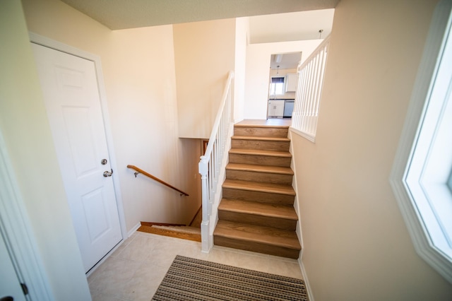 staircase featuring tile patterned floors and baseboards