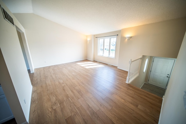 unfurnished living room with visible vents, wood finished floors, and vaulted ceiling