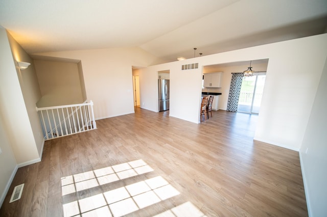 unfurnished living room with baseboards, visible vents, light wood finished floors, and vaulted ceiling