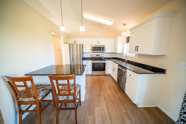 kitchen featuring stainless steel appliances, dark countertops, vaulted ceiling, and light wood-style flooring