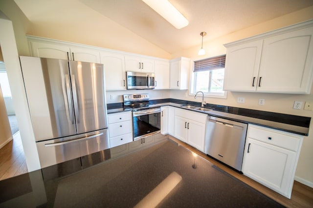 kitchen with a sink, lofted ceiling, dark countertops, and stainless steel appliances