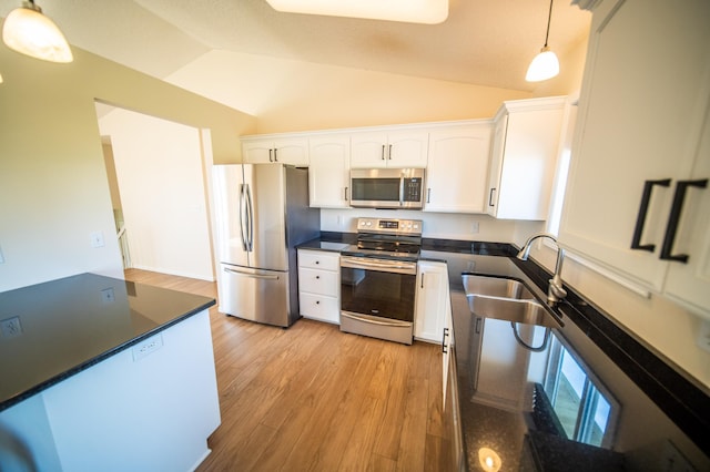 kitchen featuring decorative light fixtures, dark countertops, a sink, white cabinets, and stainless steel appliances