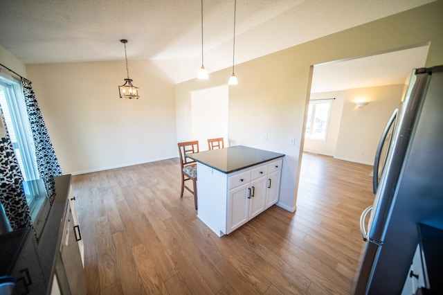 kitchen with freestanding refrigerator, white cabinetry, plenty of natural light, and lofted ceiling