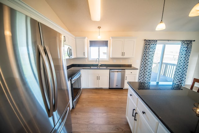 kitchen featuring dark countertops, dark wood-style floors, white cabinets, a sink, and stainless steel appliances
