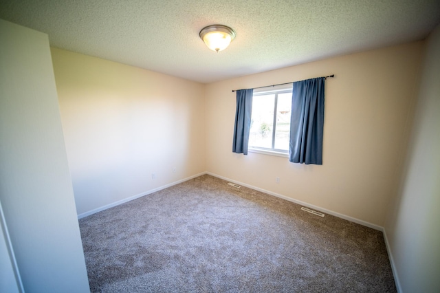 spare room with visible vents, carpet flooring, a textured ceiling, and baseboards
