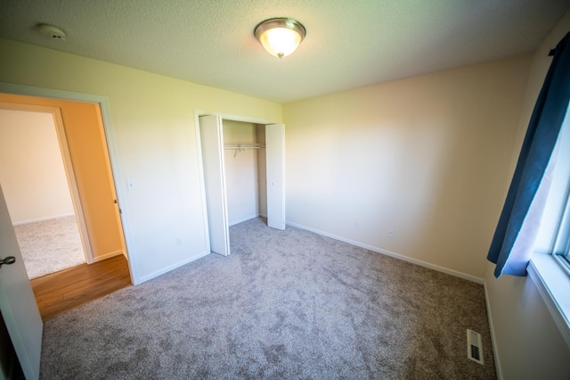 unfurnished bedroom featuring baseboards, carpet, a closet, and visible vents