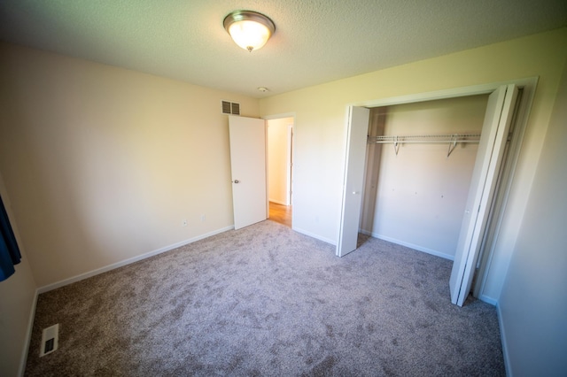 unfurnished bedroom with a closet, carpet flooring, a textured ceiling, and visible vents