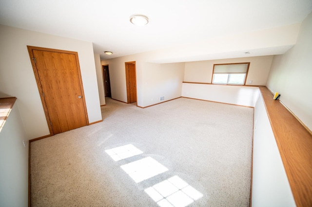 spare room featuring baseboards and light carpet