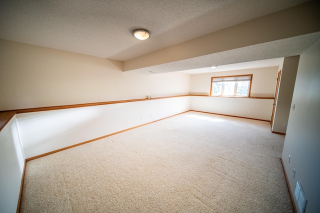 spare room with baseboards, carpet flooring, a textured ceiling, and visible vents
